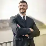 Oliver Grant, Client Success Director at Infinite Corporate, smiling with arms folded outdoors