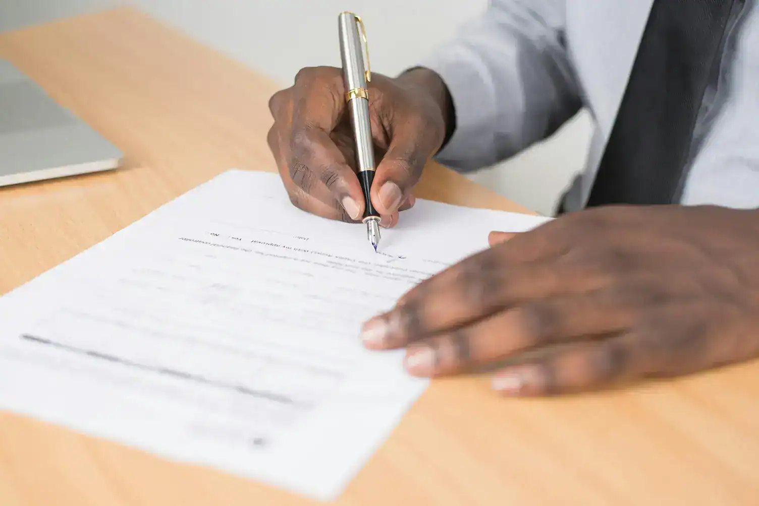 Close-up of a person signing official company documents with a fountain pen—illustrating friendly help with filings and paperwork (Services – Infinite Corporate).